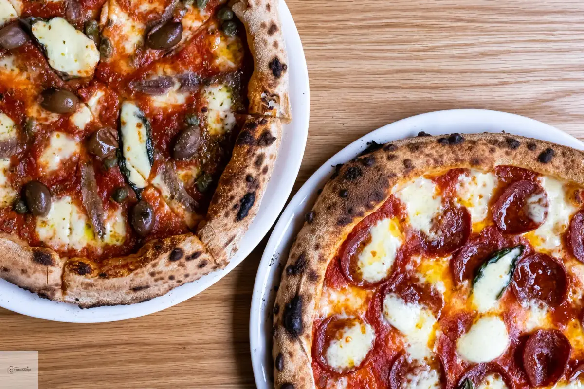 Two authentic wood-fired Neapolitan pizzas — puttanesca with olives and capers, and salami diavola — freshly made at a Sydney catering event